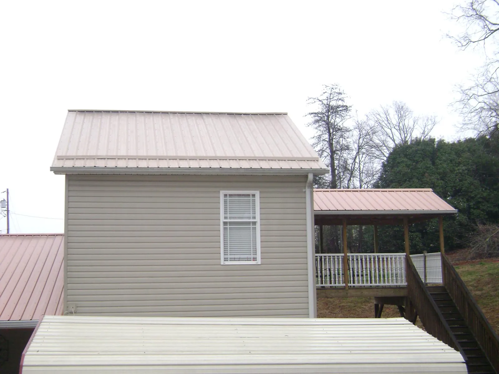 Tan metal roofs on a two story addition and attached porch, from a Roof Replacement job in Arizona City