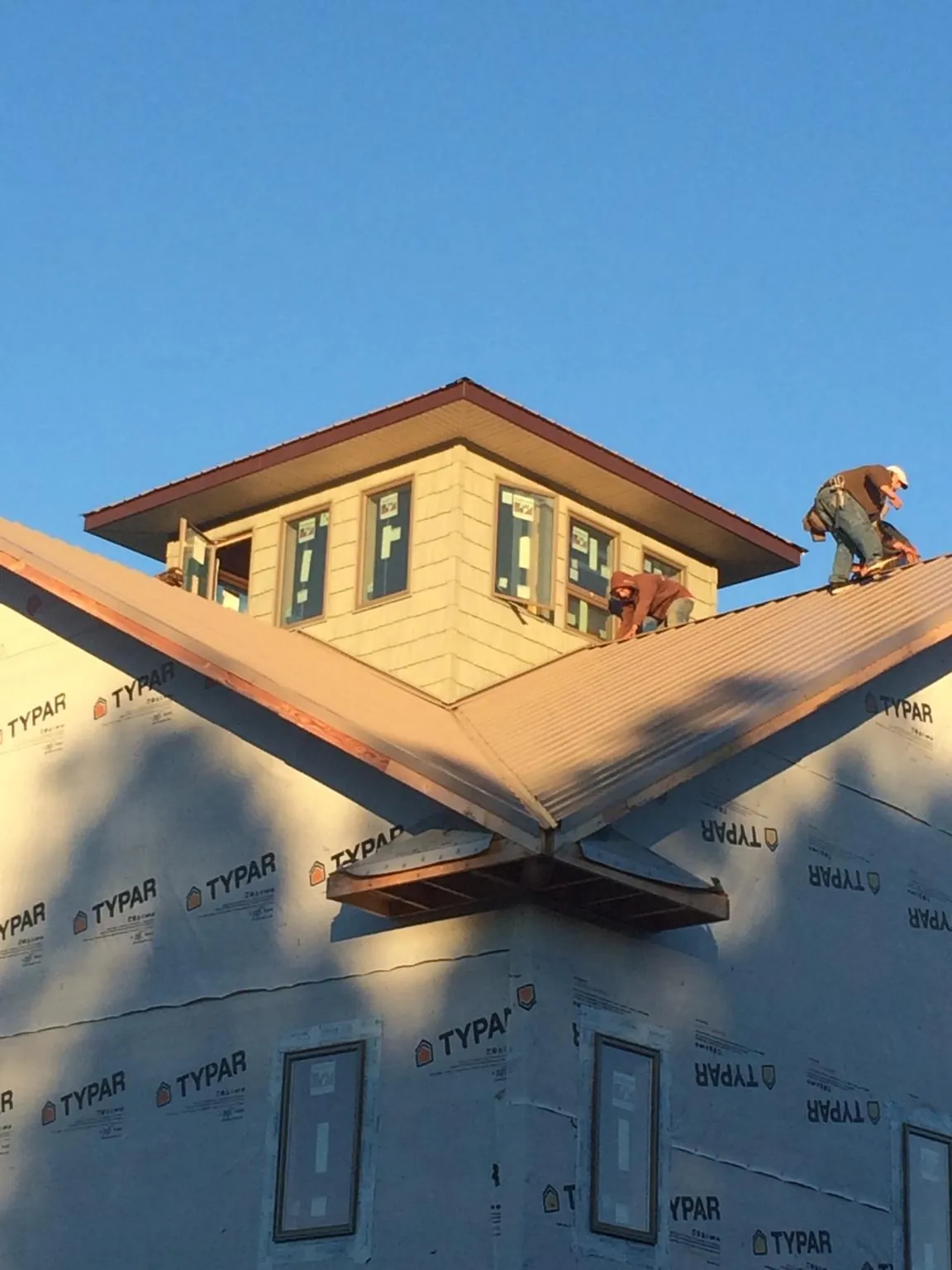 Roofers working around a rooftop cupola on a new metal roof at sunset — Roof Waterproofing in Arizona City by Roofing Brothers